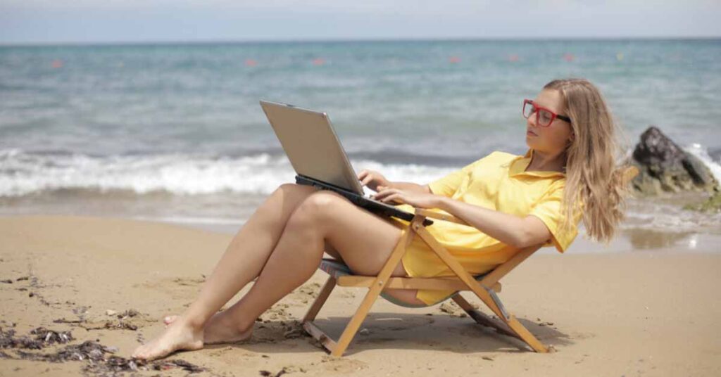 Image of woman on the beach with laptop using a website builder