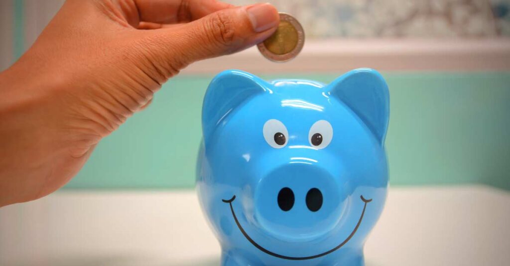 Hand putting money into piggy bank