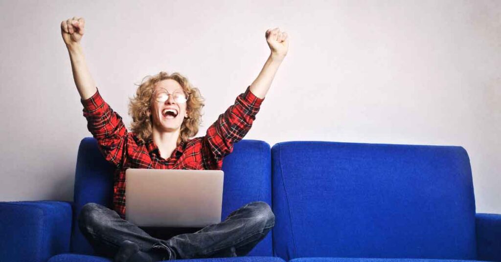 Person sitting on couch with laptop celebrating