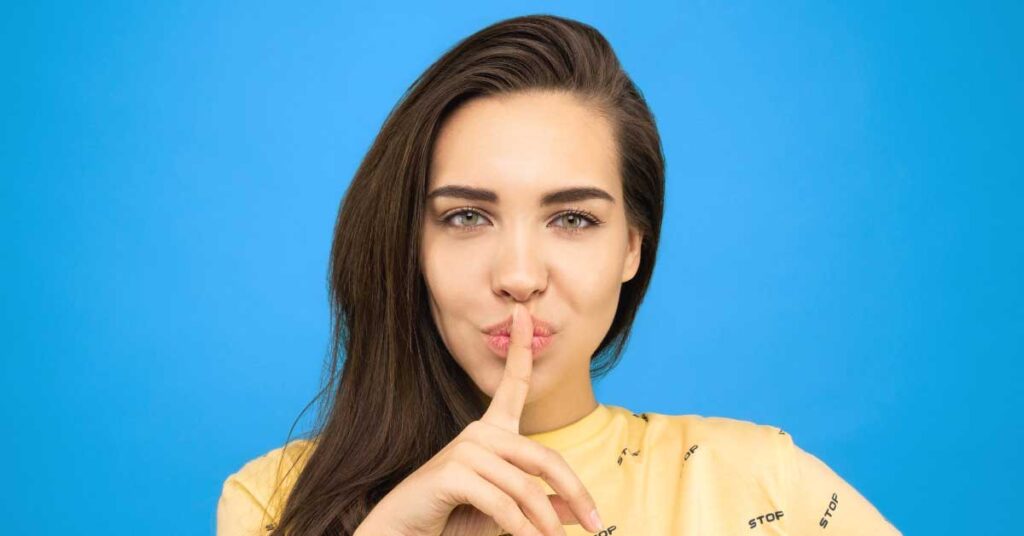 Woman with her finger in front of her lips keeping her password secret